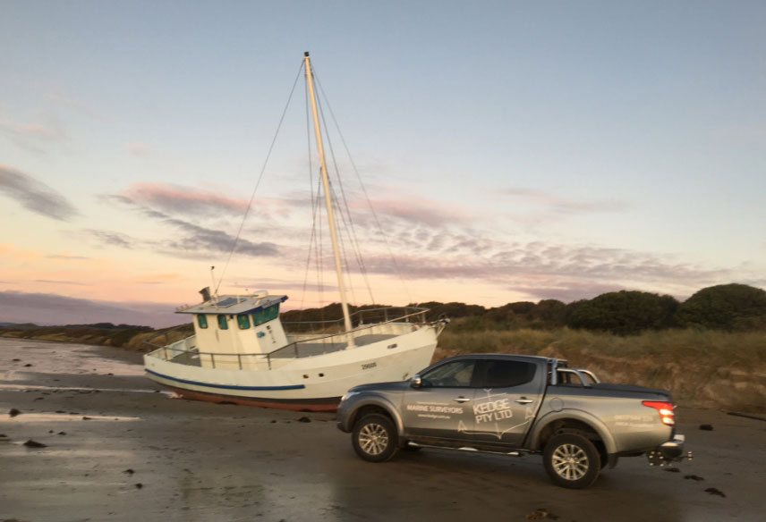 Grounded commercial fishing vessel next to Marine Surveyor's car.